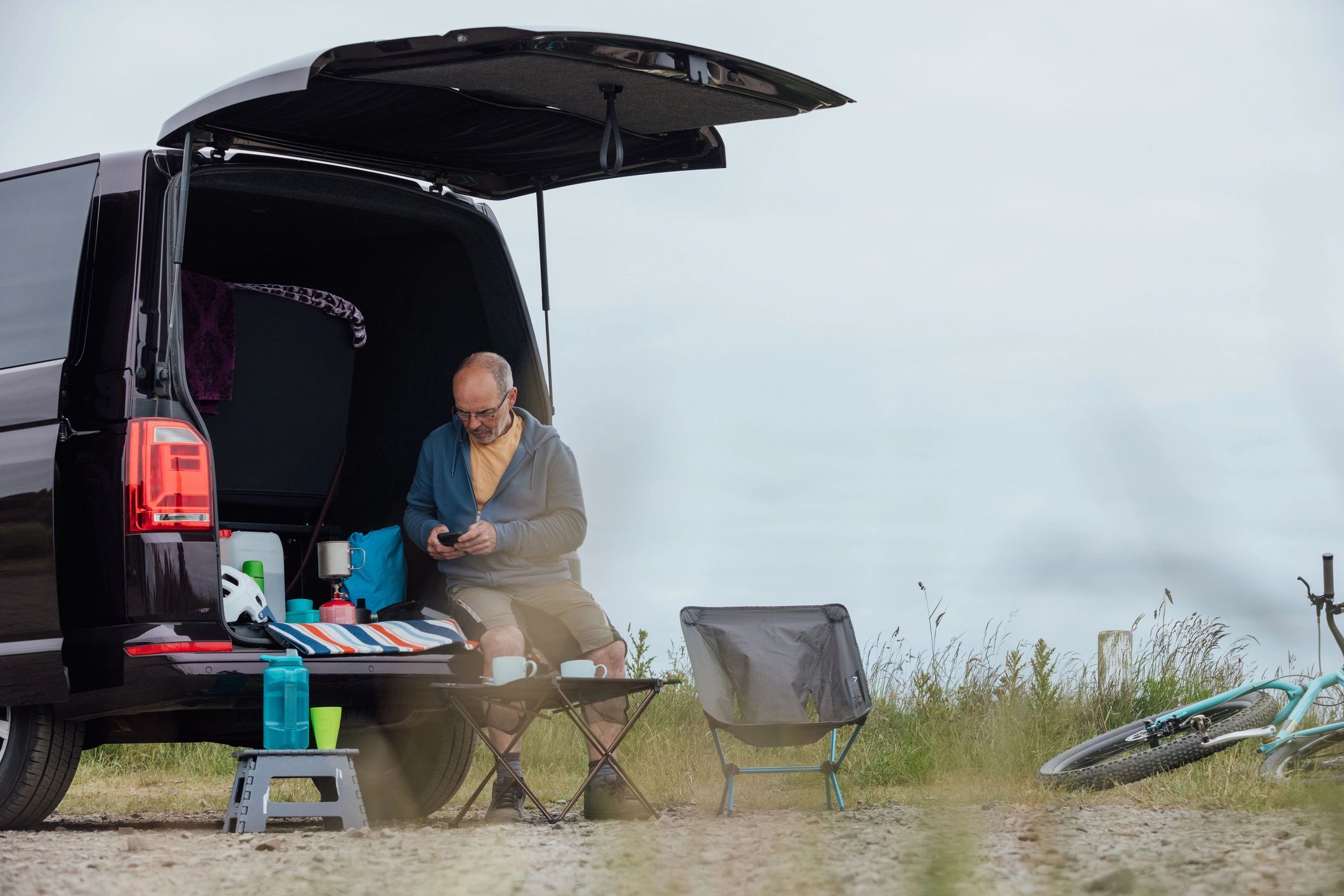 RV owner sitting near a camper van by the coast